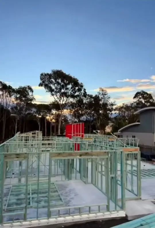Wall frames standing on a concrete slab at dusk, with gum trees behind.